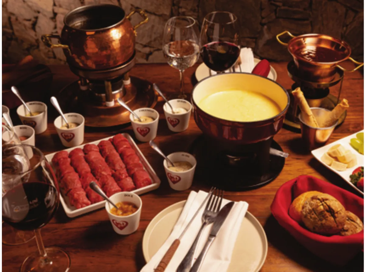 Mesa de fondue servida no Chalezinho, com panelas de queijo e carne